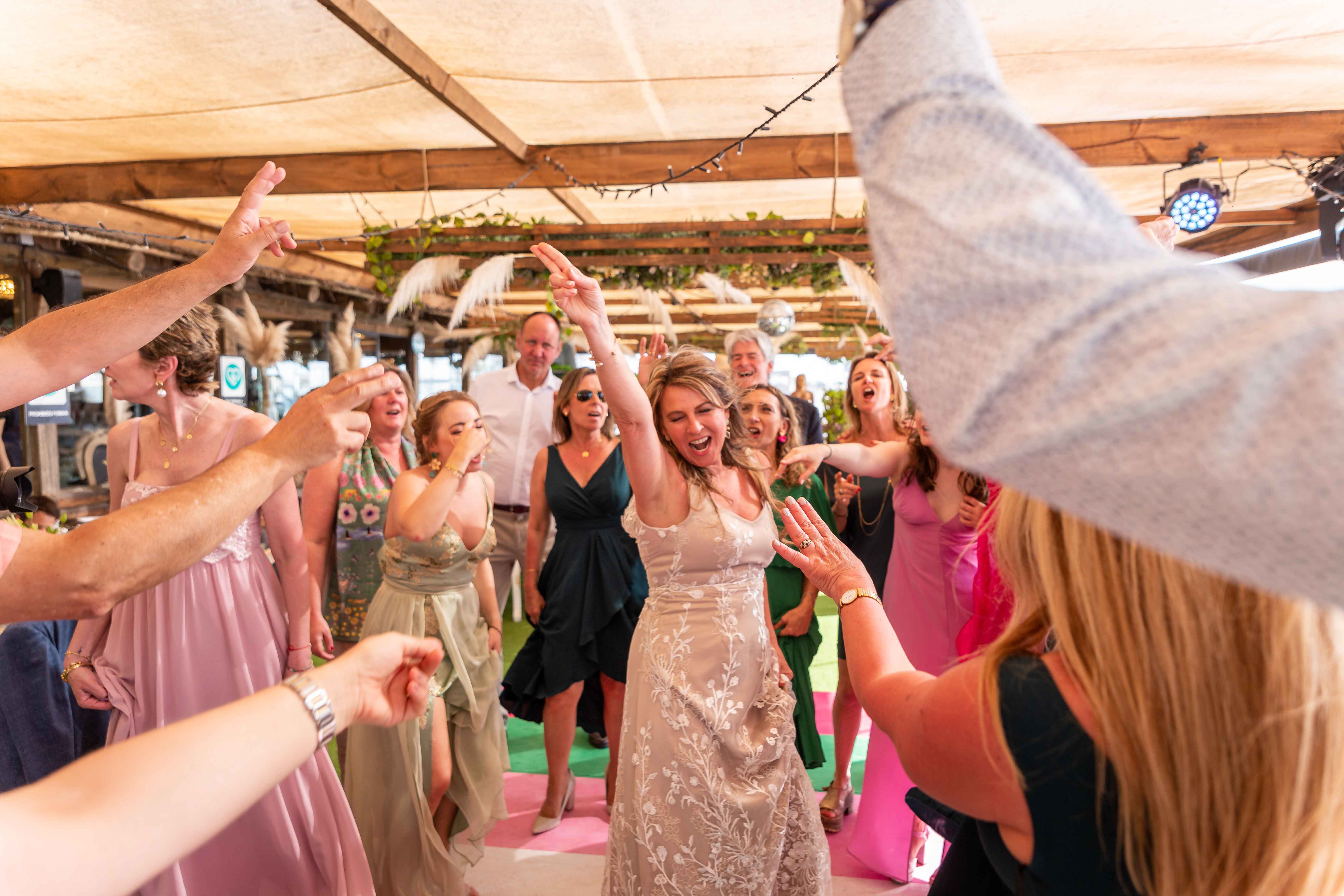 Una escena alegre en una recepción de boda, con un grupo de personas bailando y celebrando a la novia.