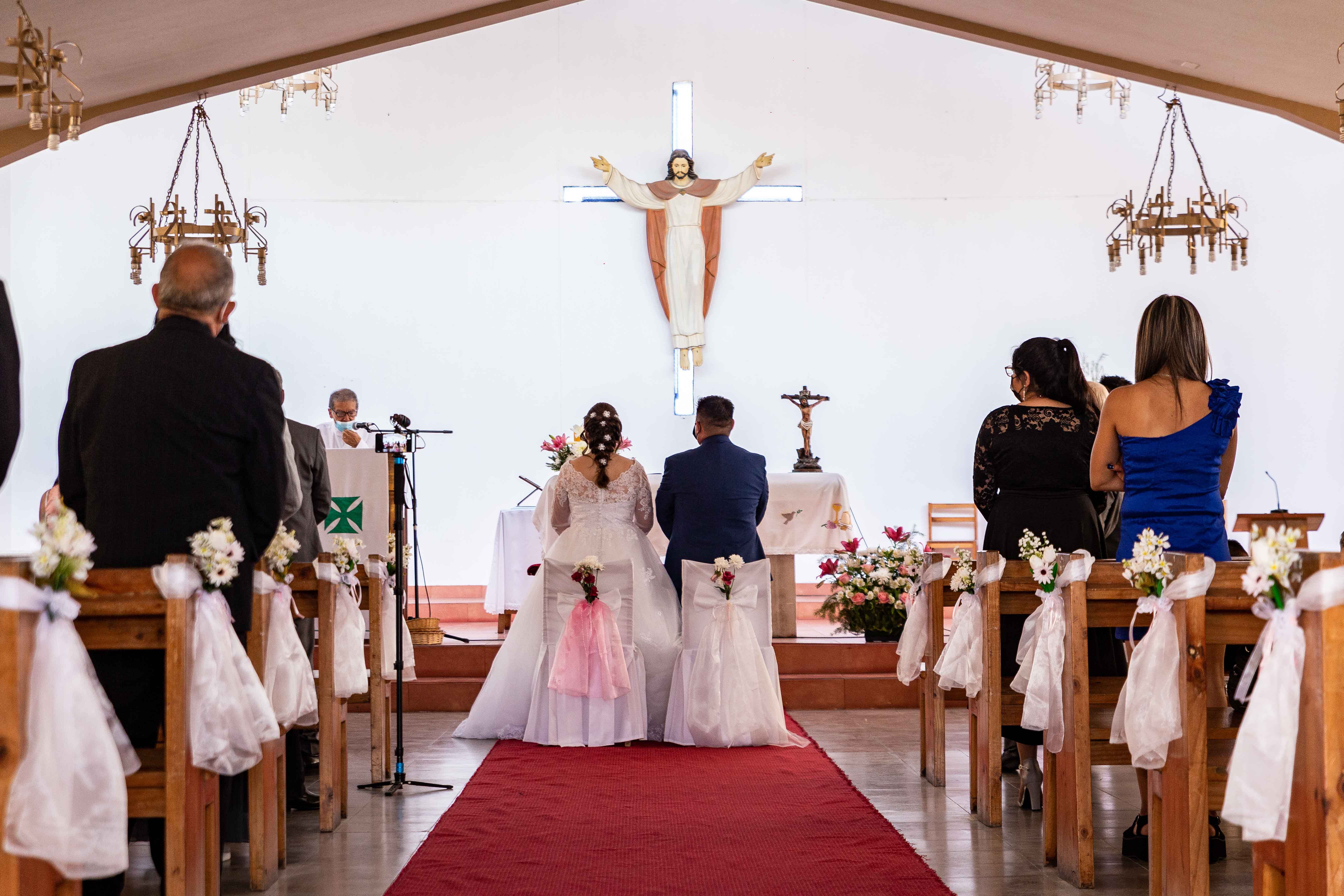 Pareja de novios sentados frente al altar esperando para recibir la bendición del sacerdote y recibirse como marido y mujer.