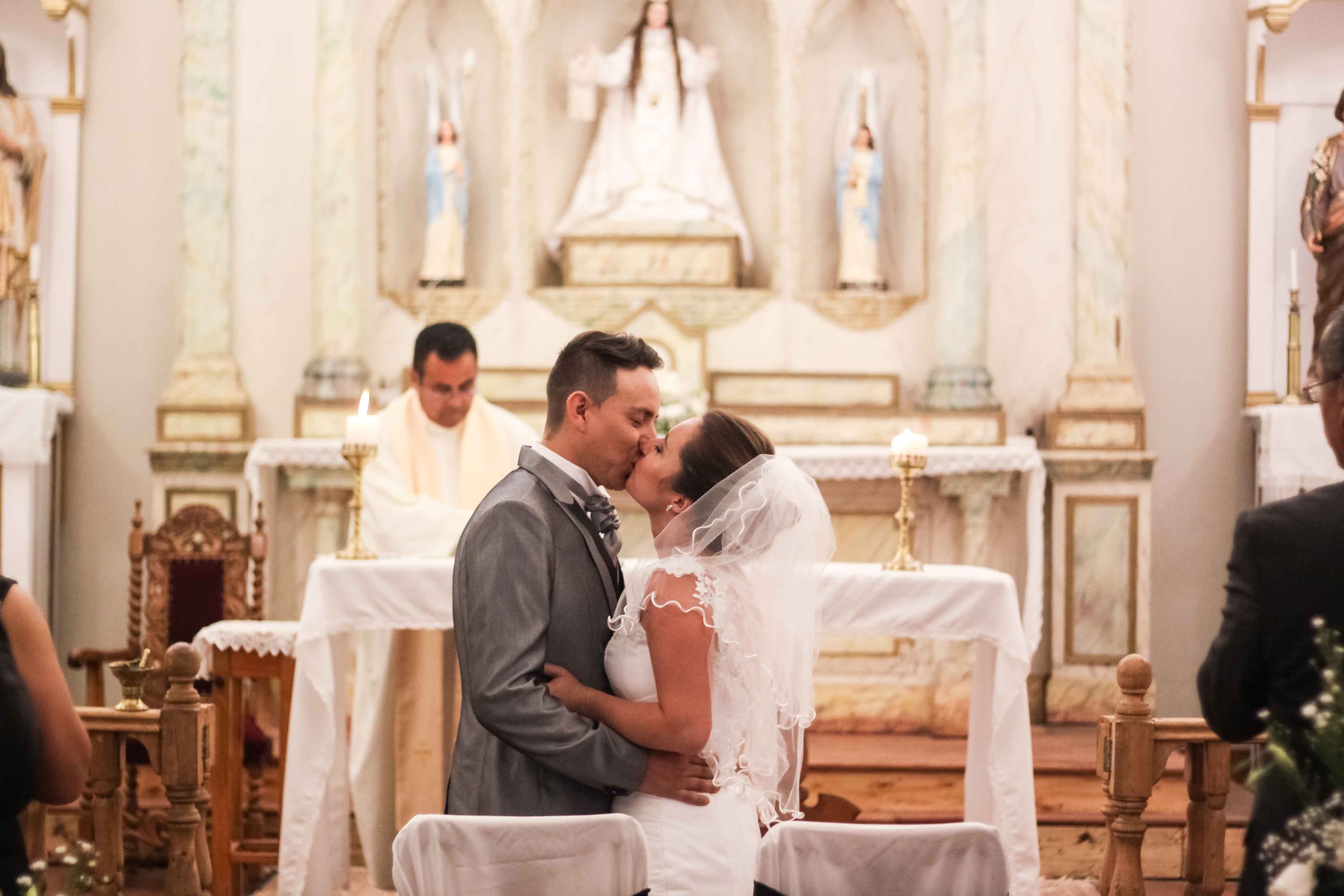 Marido y Mujer besándose en el altar de una iglesia momentos después de casarse.