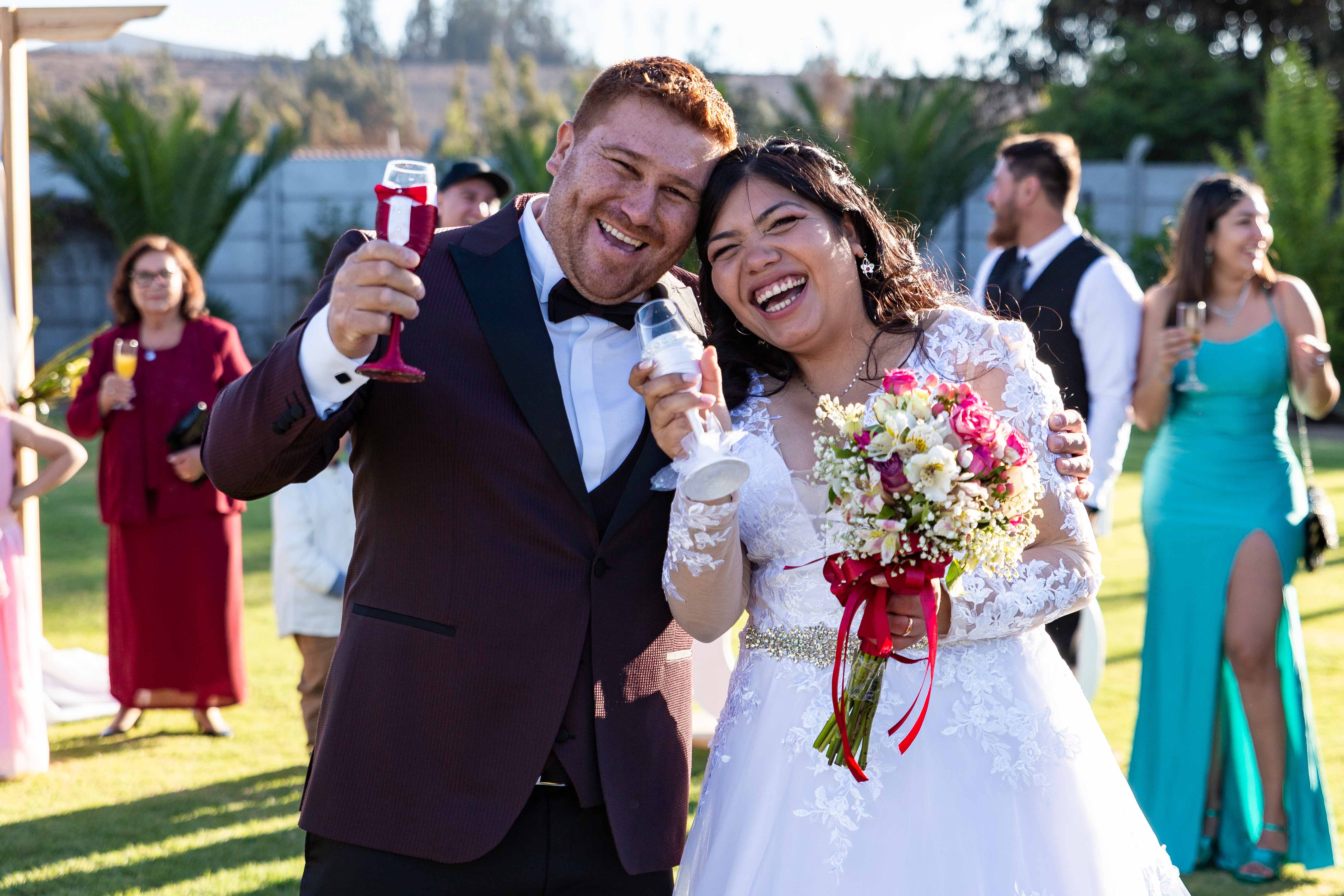 Una pareja de recién casados sonriendo y brindando con copas de champagne, capturando un hermoso momento el día de su boda.
