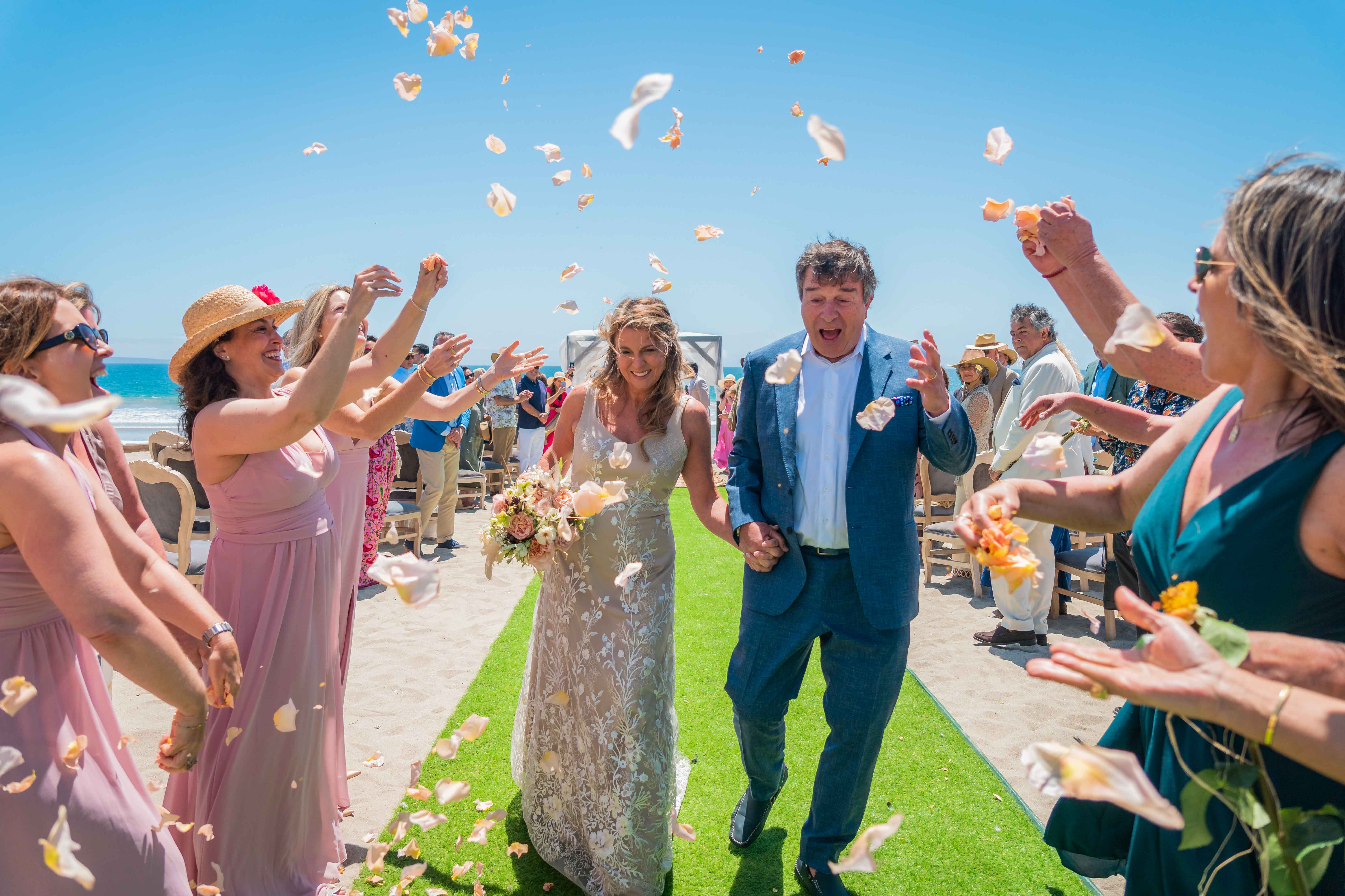 Unos novios alegres celebran su boda, rodeados de confeti de colores lanzado por las damas de honor.